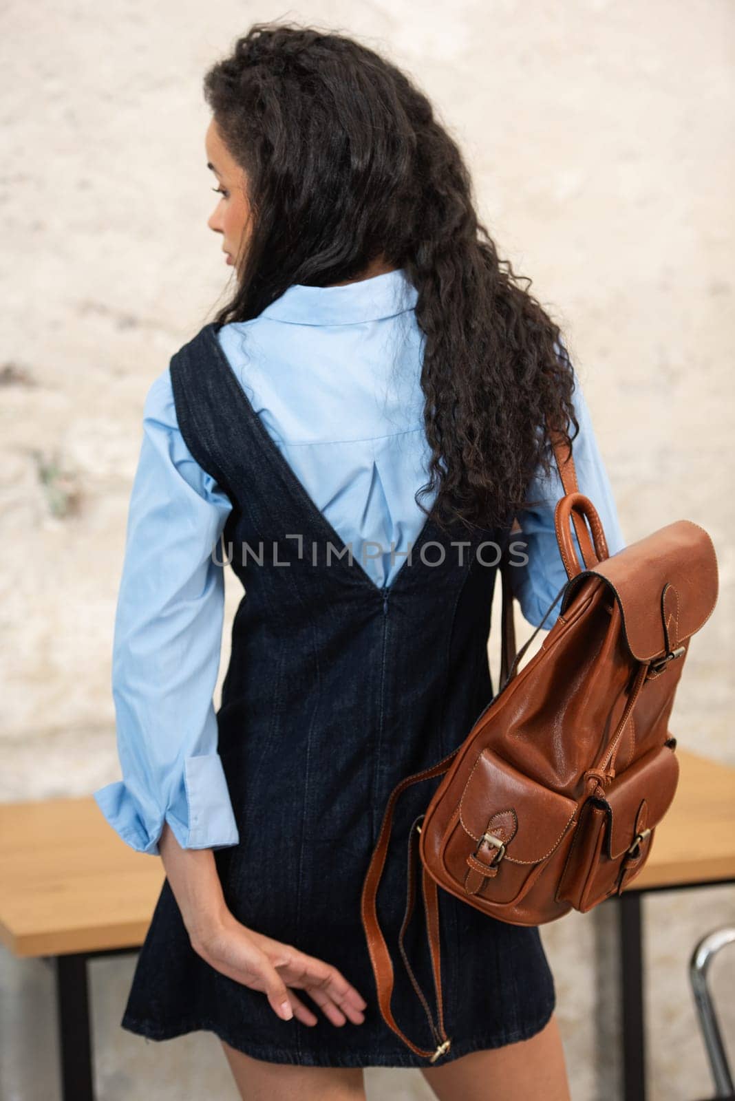 A fashionable model confidently showcasing a modern outfit while sporting a brown backpack accessory