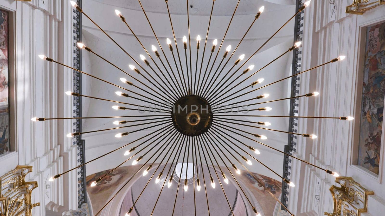 Modern round chandelier hanging from ceiling in church, illuminating interior with warm light