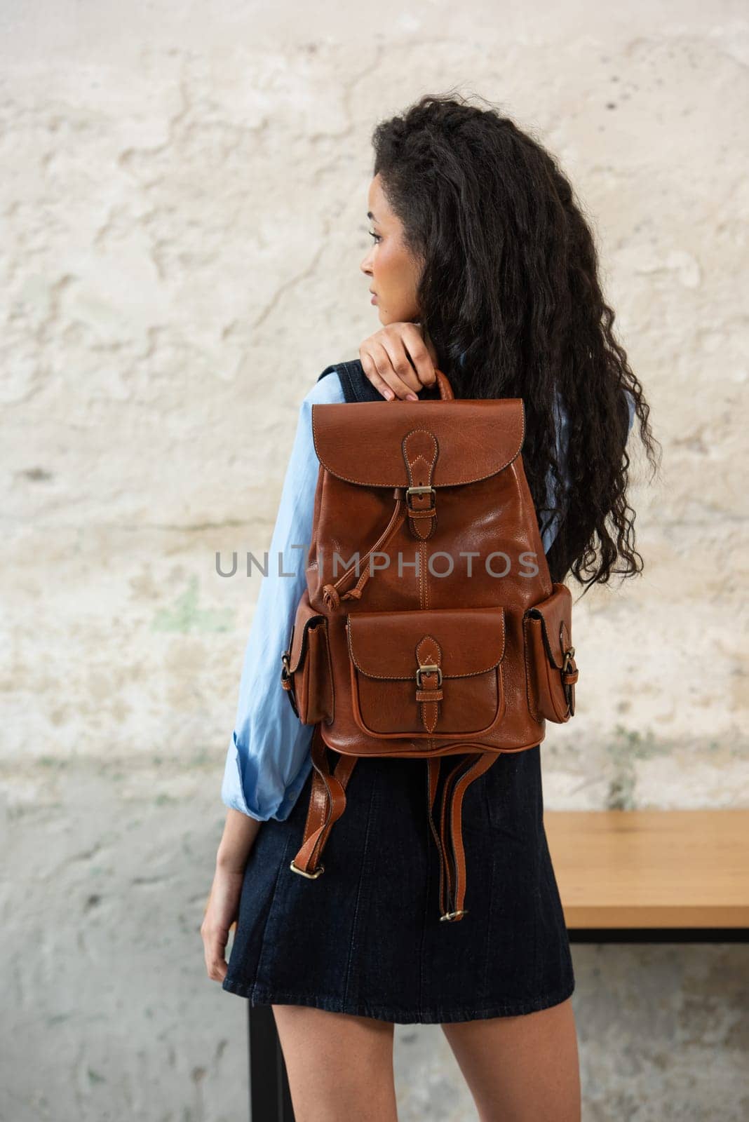A fashionable model confidently showcasing a modern outfit while sporting a brown backpack accessory