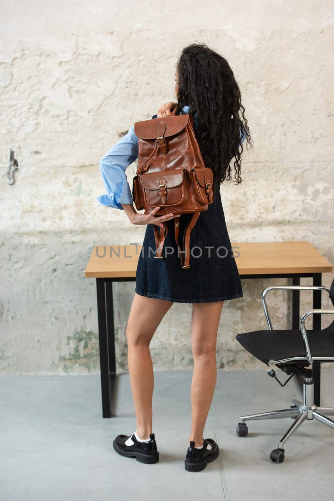 A fashionable model confidently showcasing a modern outfit while sporting a brown backpack accessory