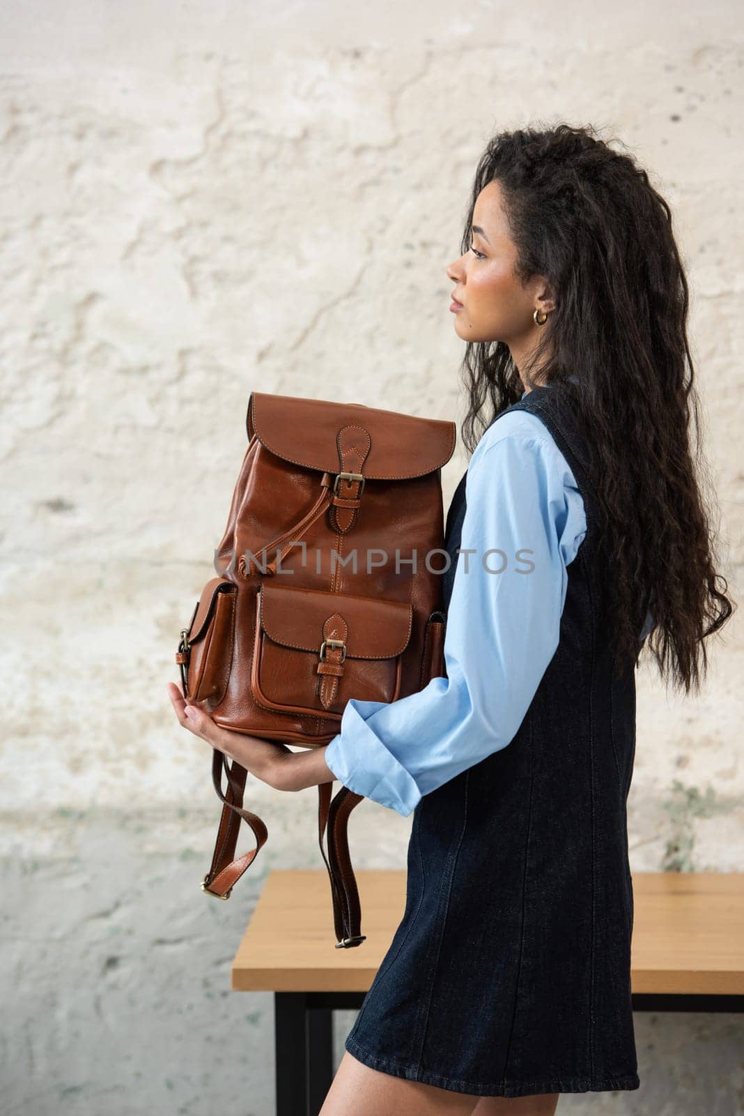 A fashionable model confidently showcasing a modern outfit while sporting a brown backpack accessory