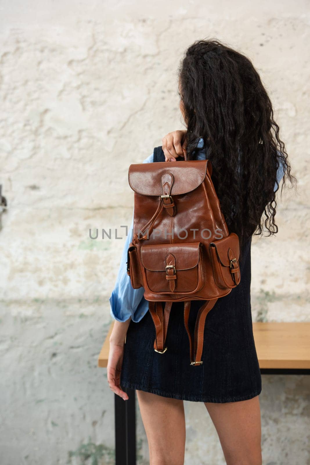 A fashionable model confidently showcasing a modern outfit while sporting a brown backpack accessory
