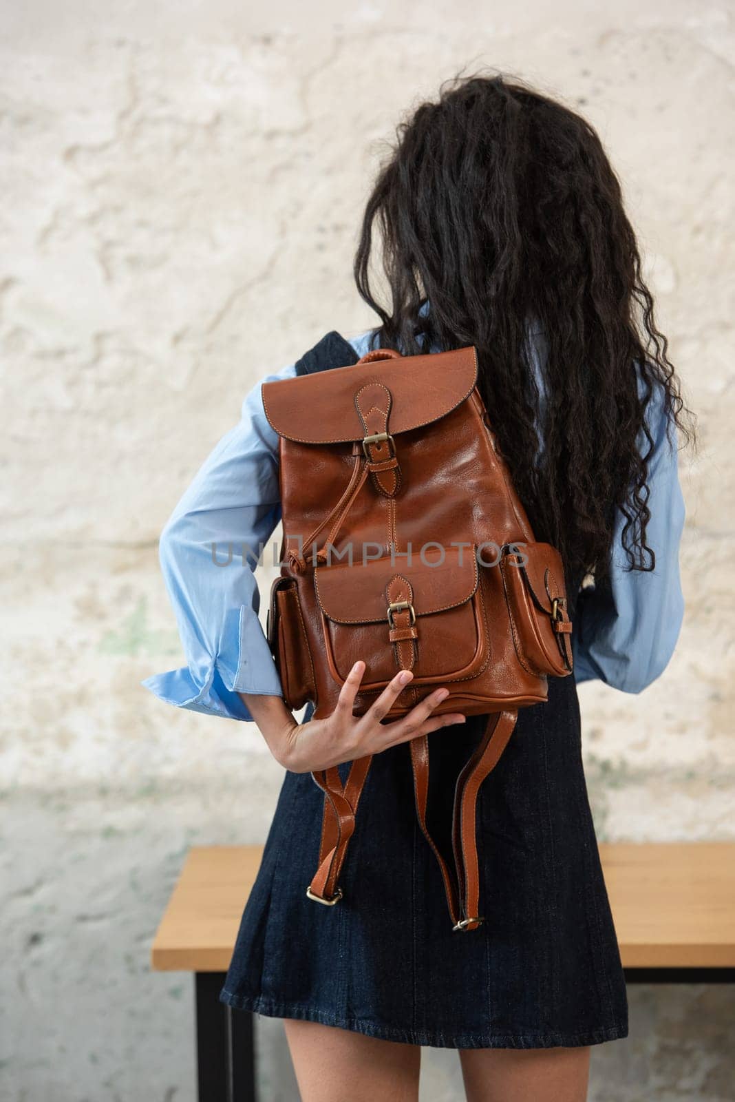 A fashionable model confidently showcasing a modern outfit while sporting a brown backpack accessory