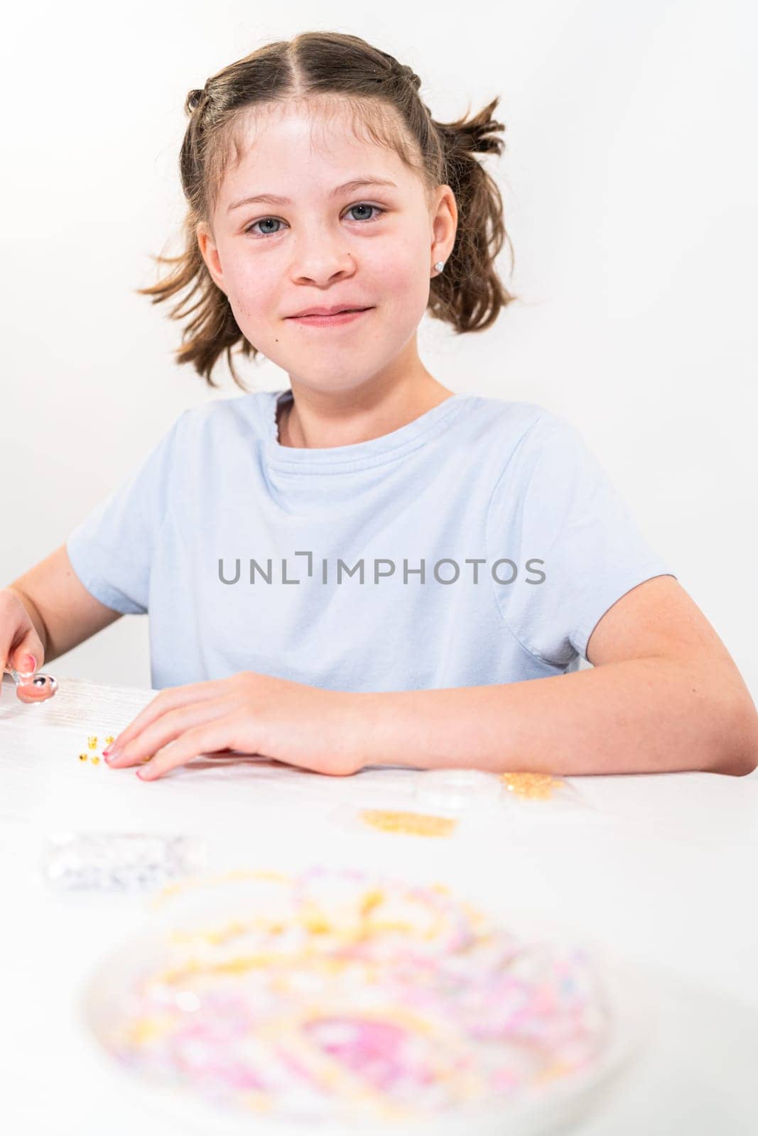 Little girl enjoys crafting colorful bracelets with vibrant clay beads set.