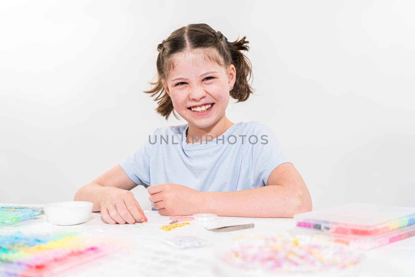 Little girl enjoys crafting colorful bracelets with vibrant clay beads set.