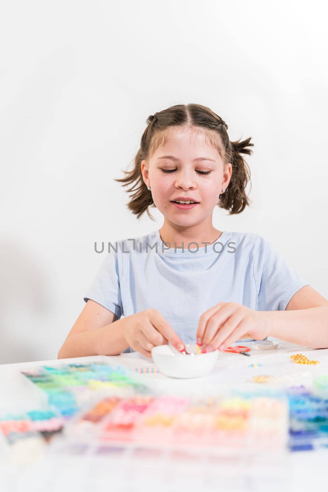 Little girl enjoys crafting colorful bracelets with vibrant clay beads set.