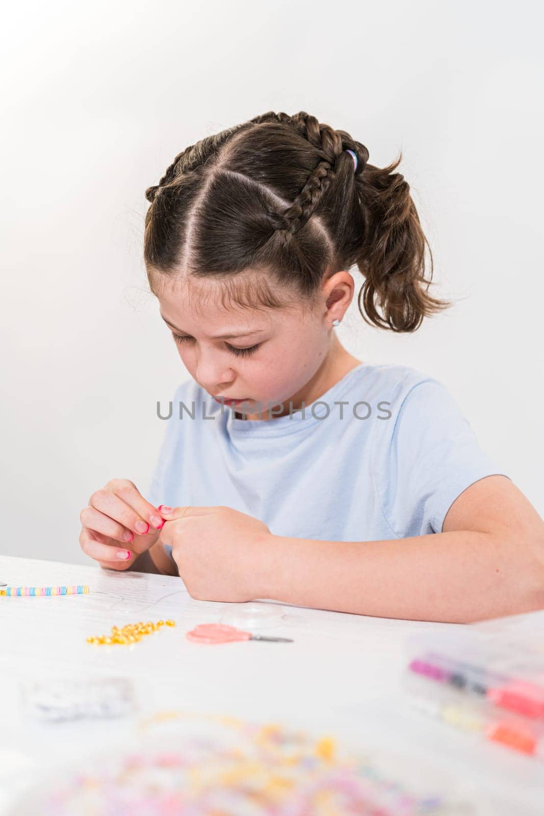 Little girl enjoys crafting colorful bracelets with vibrant clay beads set.