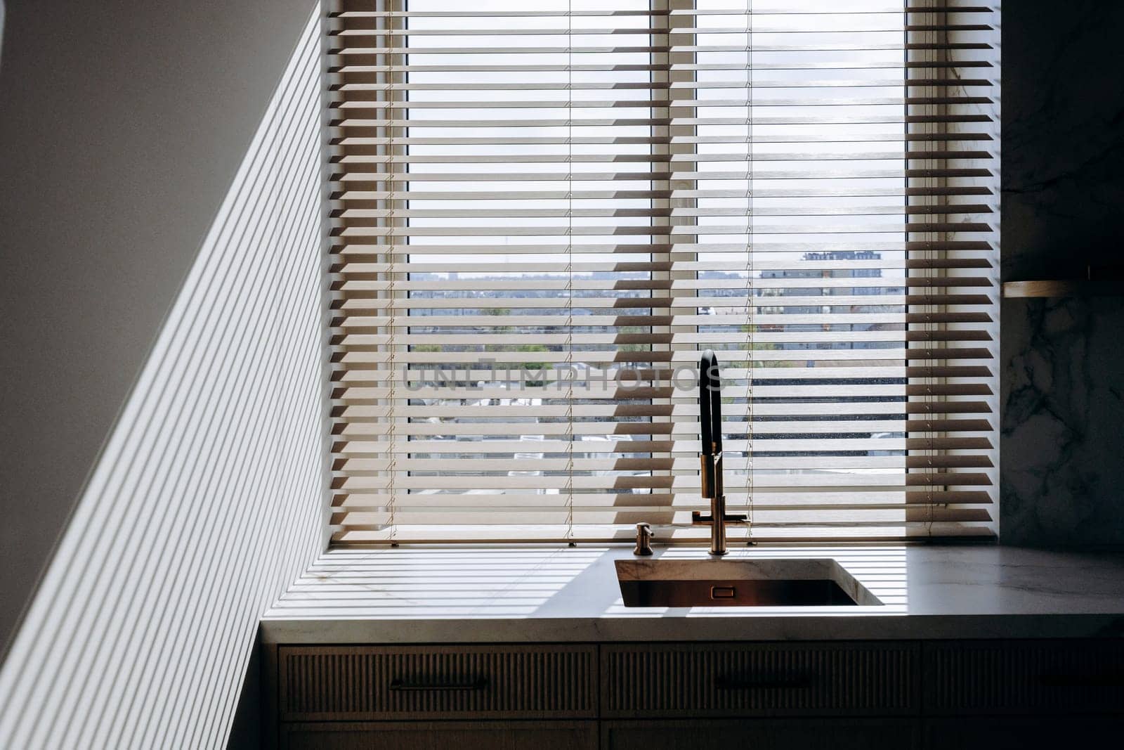 This is a cozy and functional kitchen that features both a sink for washing dishes and a window adorned with blinds for privacy