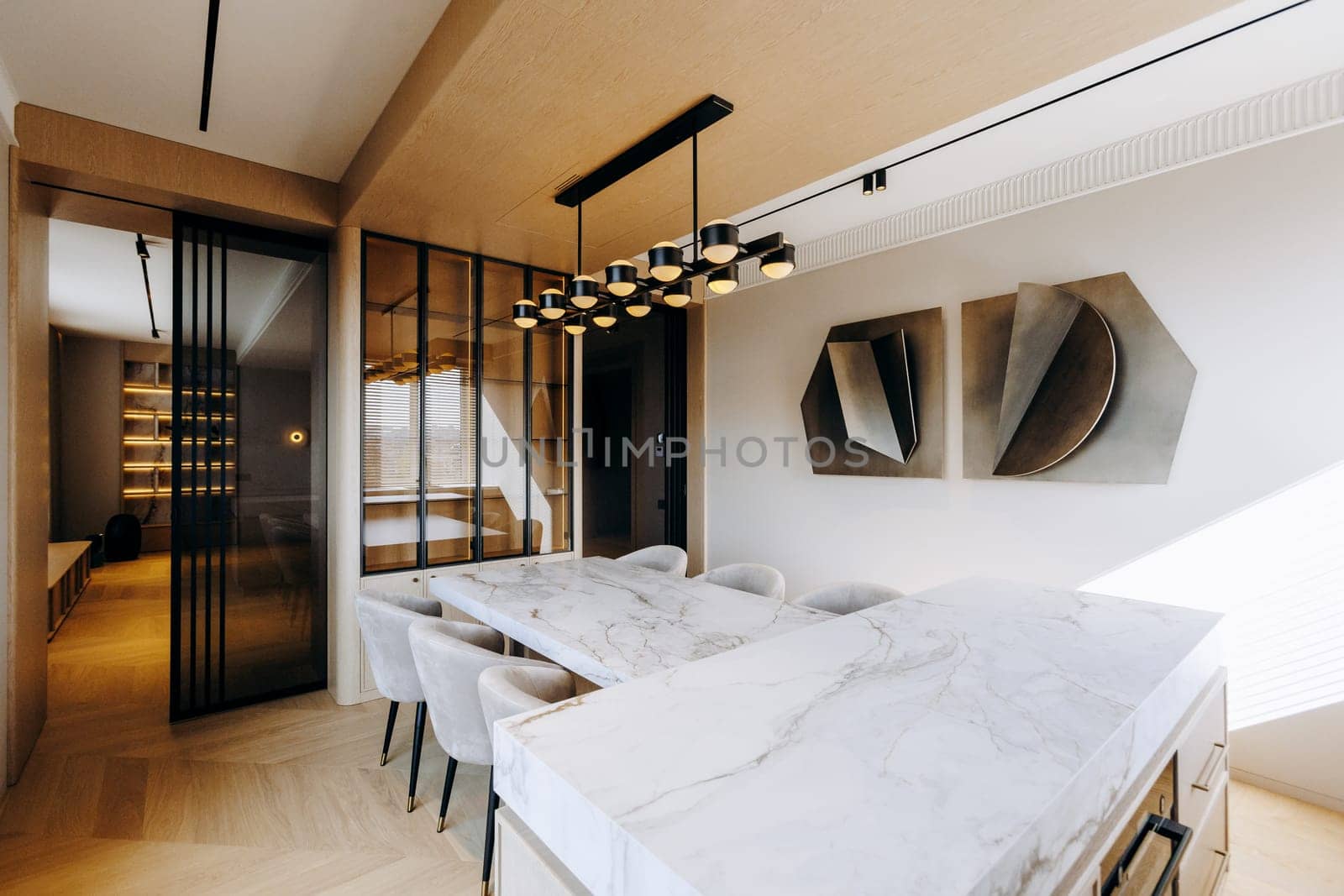 A spacious dining room featuring a large wooden table surrounded by comfortable chairs, complemented by an elegant marble countertop