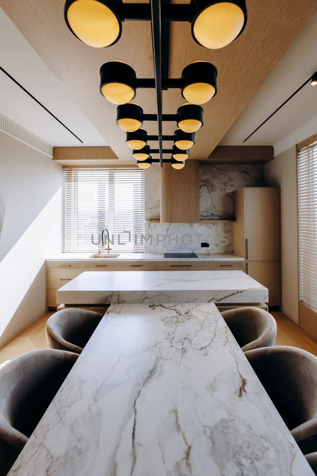A beautifully designed kitchen features a stunning marble table, complemented by elegant chairs, along with a charming chandelier gracefully hanging from the ceiling