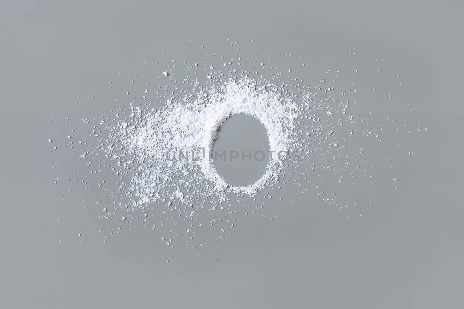 Scattered white powder on grey with copy space in middle top view. Baking soda or medical powder. Preventive medicine and healthcare, taking alternative dietary supplements. Kitchen spices