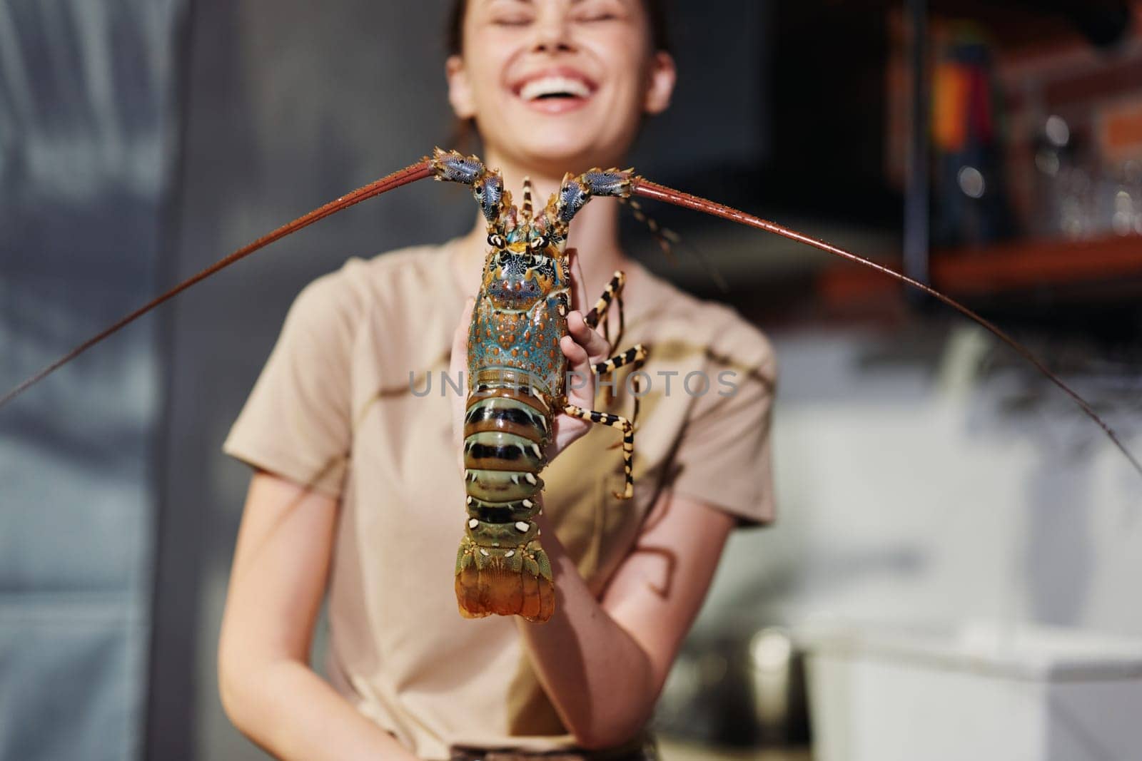 Happy woman holding a lobster and smiling at the camera with a cheerful expression, showing off her fresh seafood catch