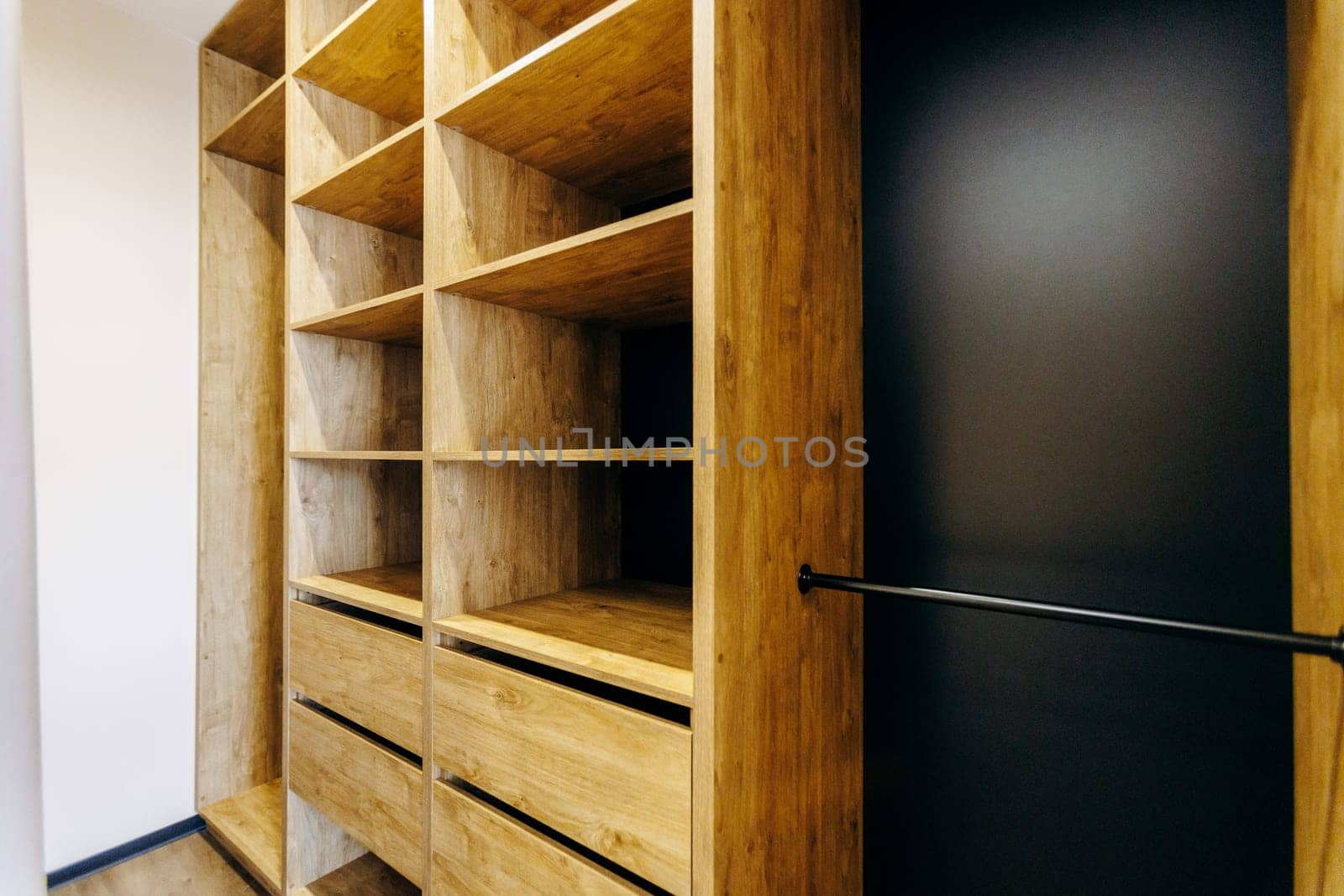 A spacious walkin closet featuring beautifully crafted wooden shelves and drawers, complemented by an elegant black door for added style