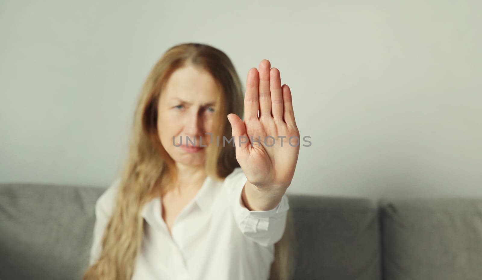 Close-up upset woman shows stop, no or enough sign with palm of hand, refusal gesture, domestic violence