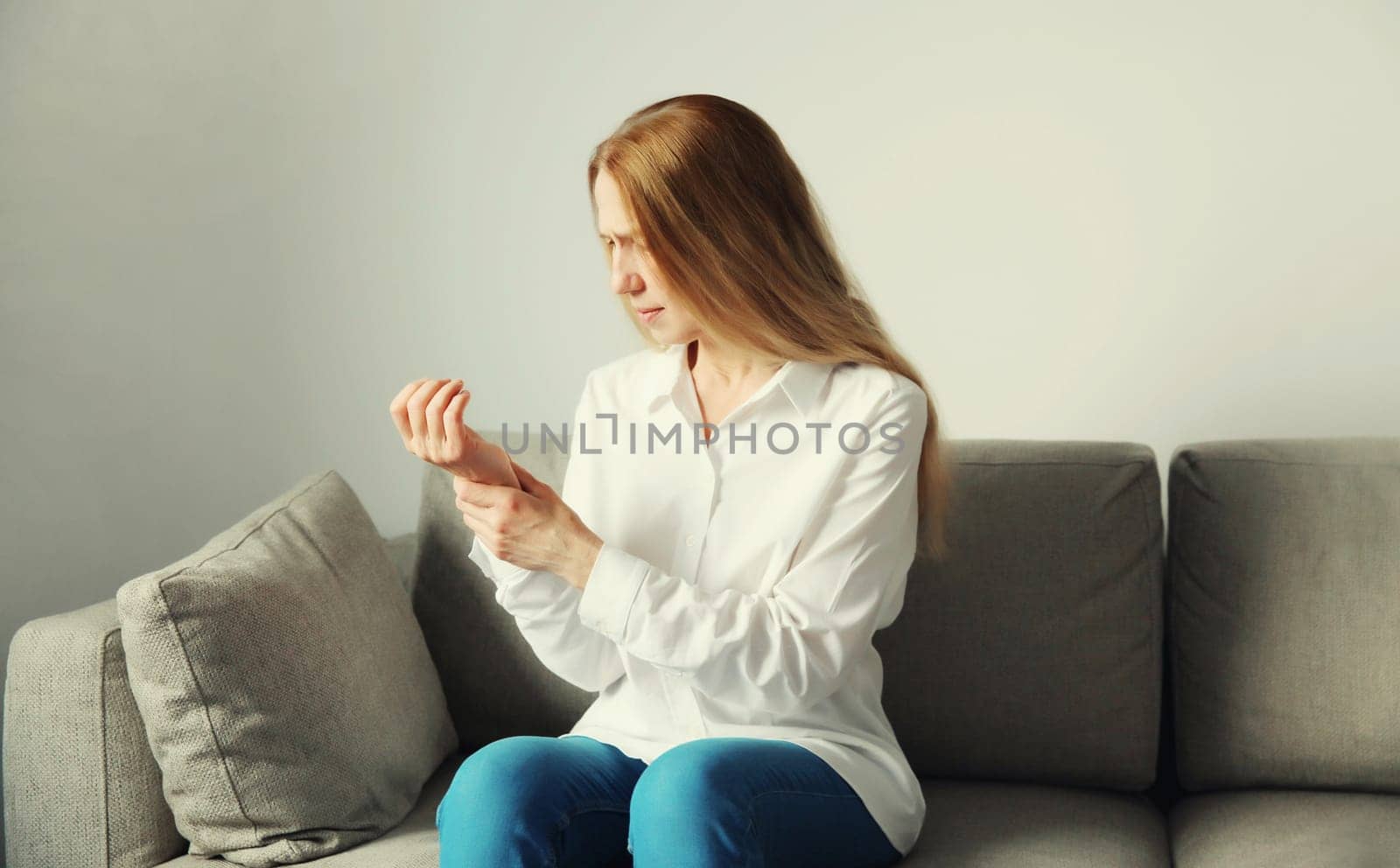Unhealthy young woman suffers from wrist pain, tunnel syndrome due to working on the computer for a long time, unwell girl touching her hand. Neuralgia and injuries concept
