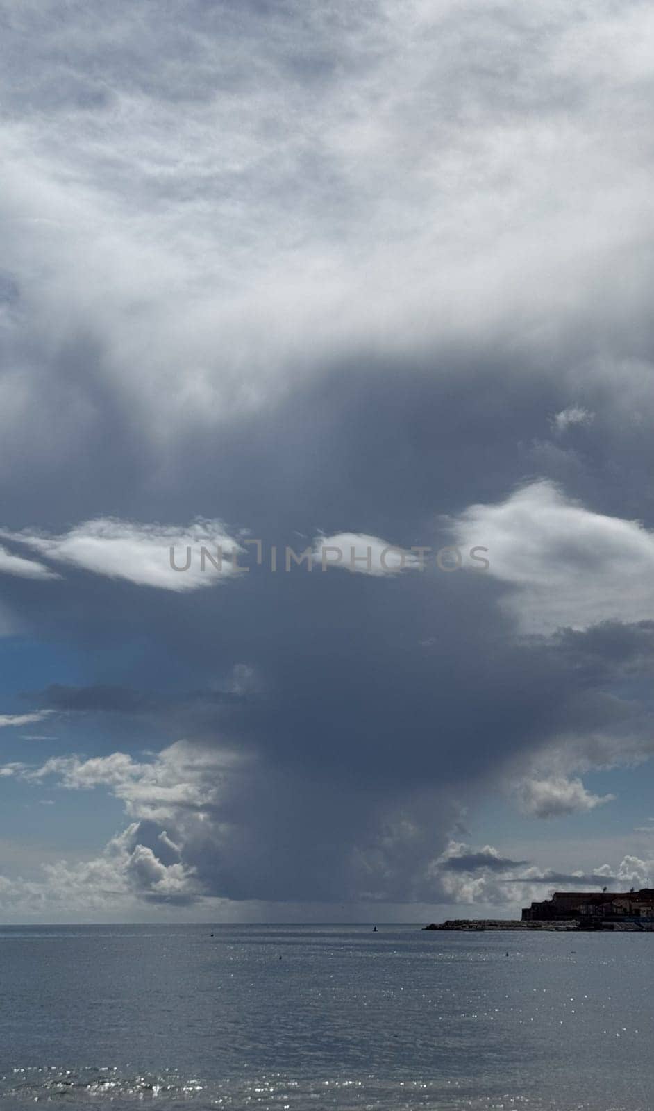 The dramatic formation of clouds over the serene seascape highlights the beauty and tranquility of nature.