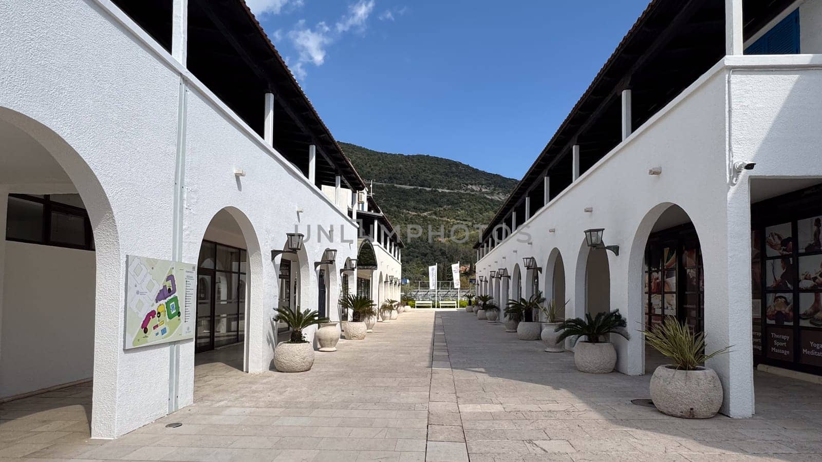 Budva, Montenegro - April 17, 2025: the street between the snow-white arches of the Hotel Aleksandar with mountain views