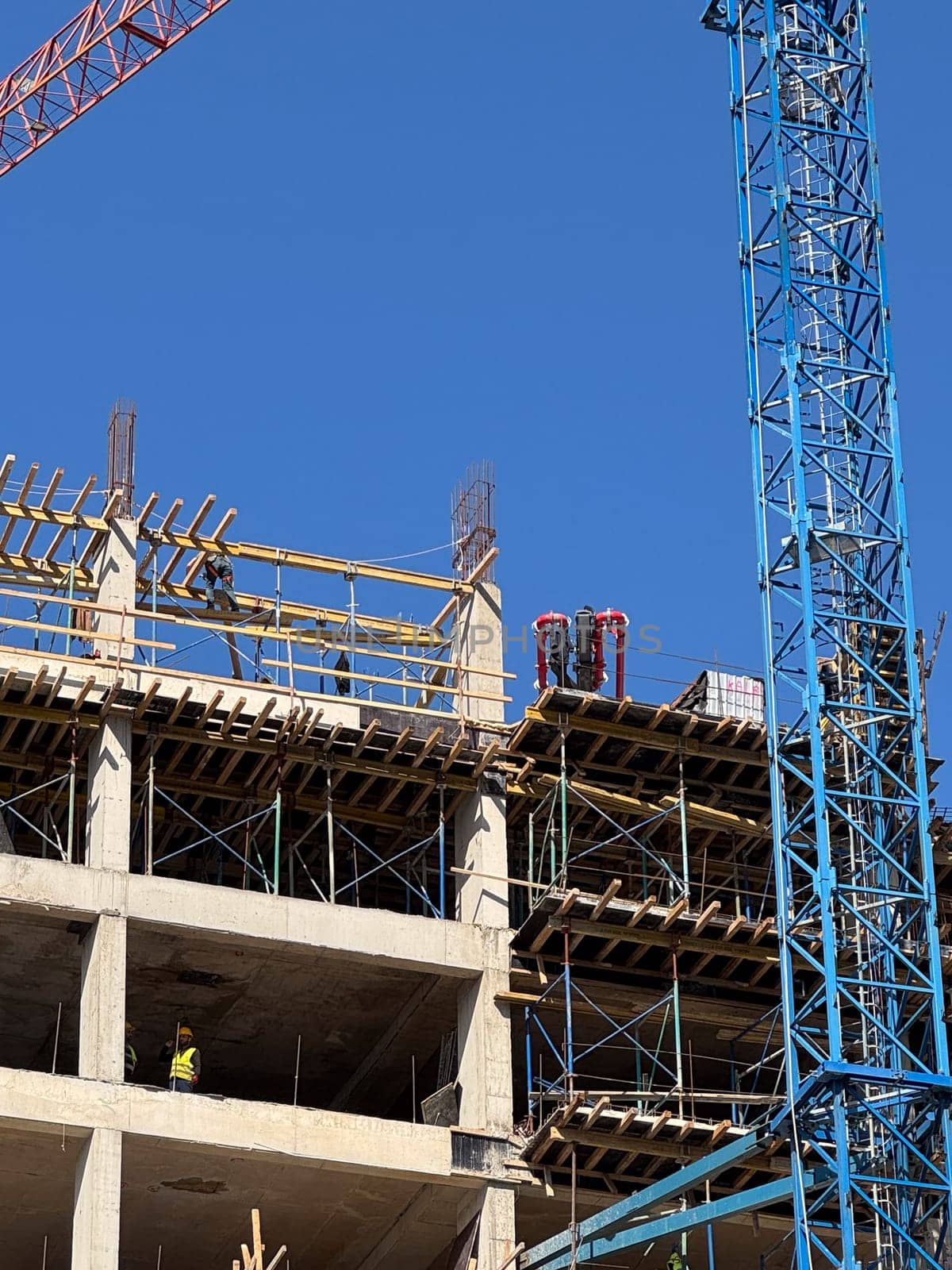 Budva, Montenegro - April 18, 2025: Construction workers work at the swissotel construction site, using a crane and scaffolding to complete their project with teamwork and dedication.