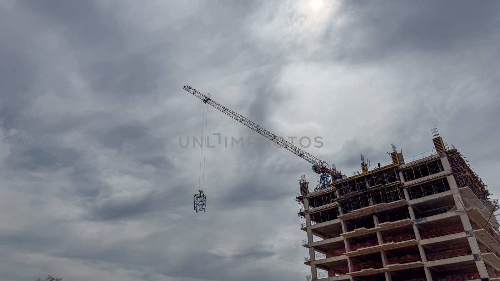Budva, Montenegro - April 18, 2025: Swissotel's construction site, featuring a crane lifting materials against a cloudy sky, highlights the city's development and architectural progress
