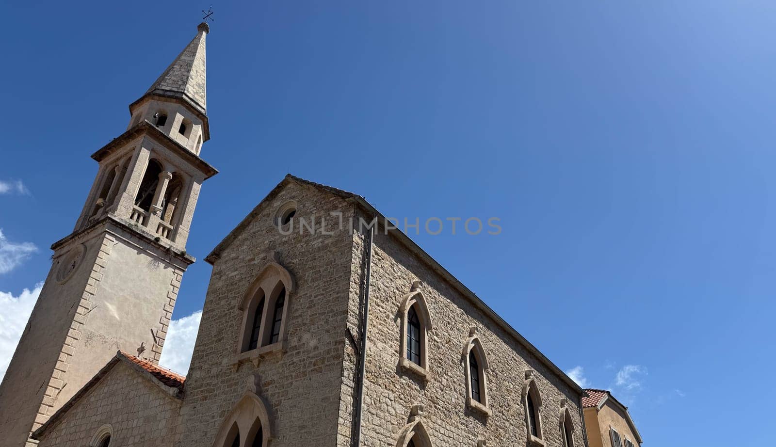 Budva, Montenegro - April 20, 2025: Historic Church of St. John the Baptist, with a blue sky in the background