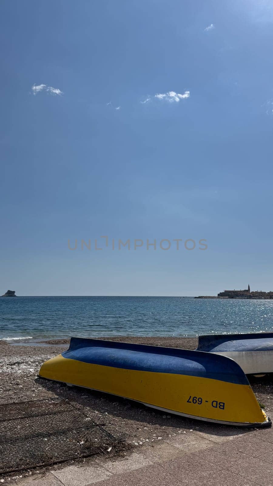 Budva, Montenegro - April 18, 2025: Colorful boats relax on the shores of the calm sea under clear skies, embodying sea relaxation and tranquility