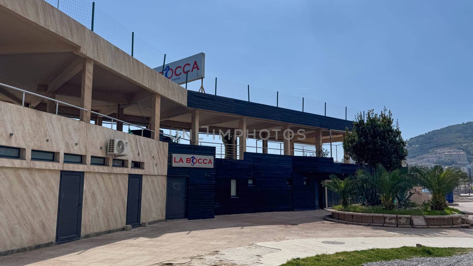 Budva, Montenegro - April 18, 2025: The exterior of La Bocca Restaurant with open upper levels and a paved walkway at the entrance under clear skies.