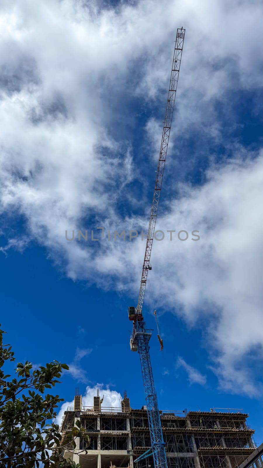Budva, Montenegro - April 18, 2025: A construction crane towers over the Swissotel construction site, framed by blue skies.Swissotel Hotels Resorts is an international chain of luxury hotels