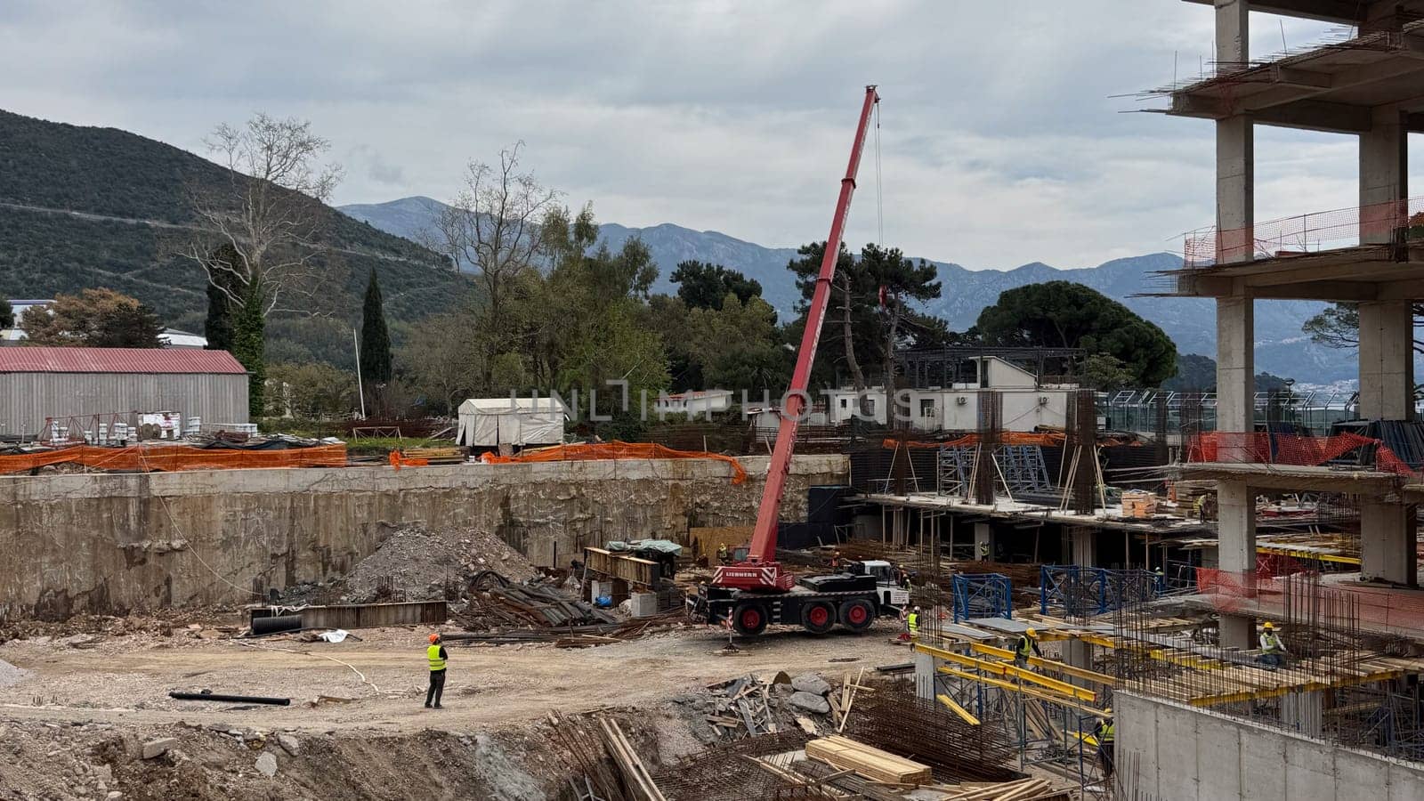 Budva, Montenegro - April 18, 2025: Construction site depicting workers and machinery in a mountainous area, highlighting the development process and growth of industry