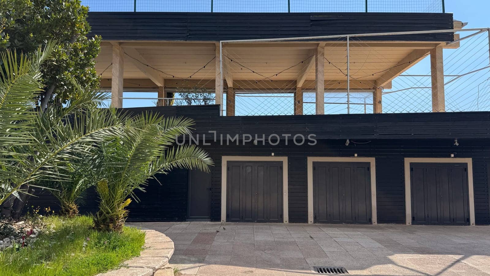 Budva, Montenegro - April 17, 2025: The modern architectural design showcases the black building with palm trees and the garage door of the La Bocca restaurant