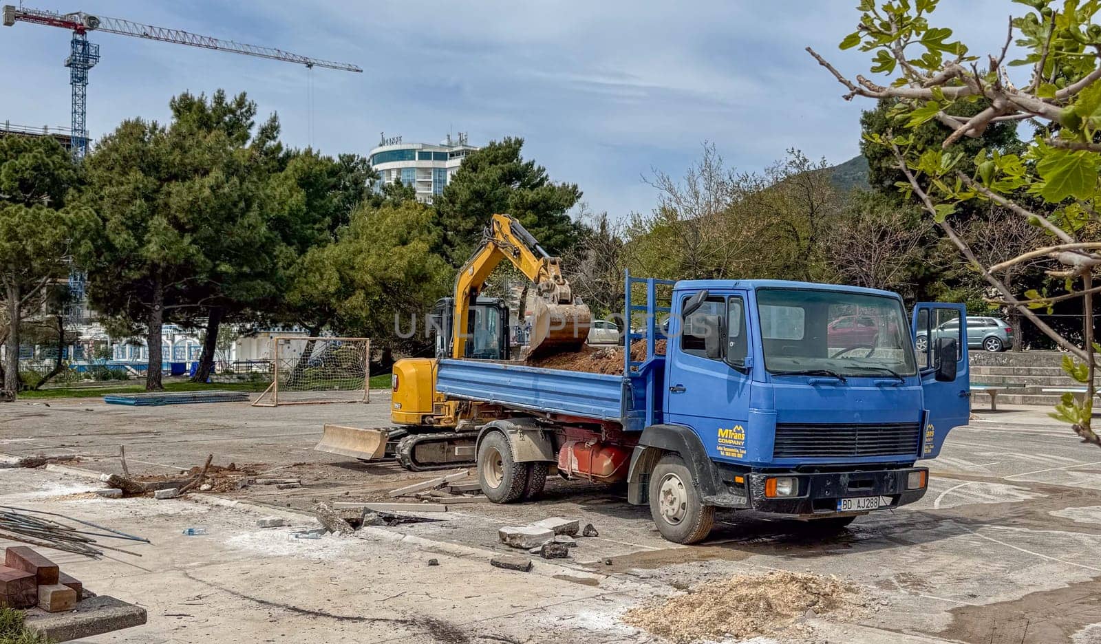 Budva, Montenegro - April 18, 2025: Construction site showcasing a blue truck alongside an excavator, emphasizing urban development and progress