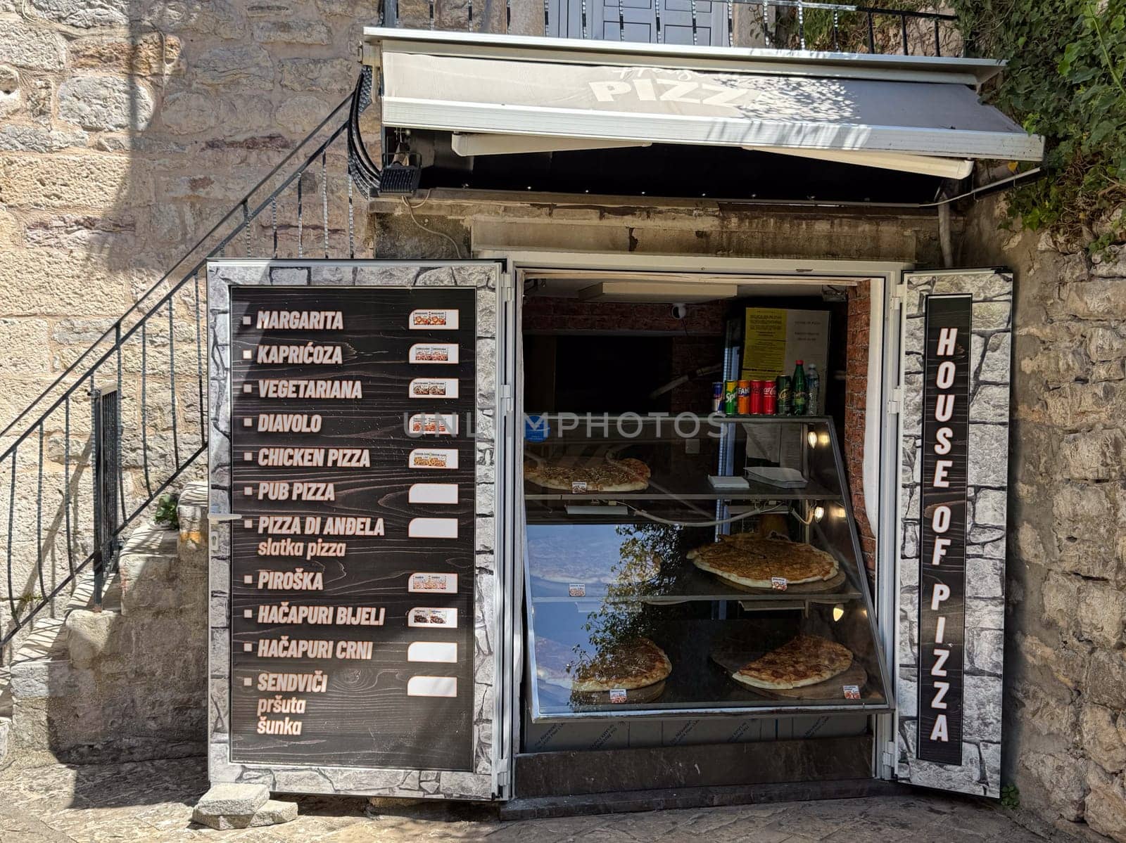 Budva, Montenegro - April 18, 2025: The House of Pizza storefront showcases a variety of pizza options, creating an inviting atmosphere for shoppers looking for a delicious meal