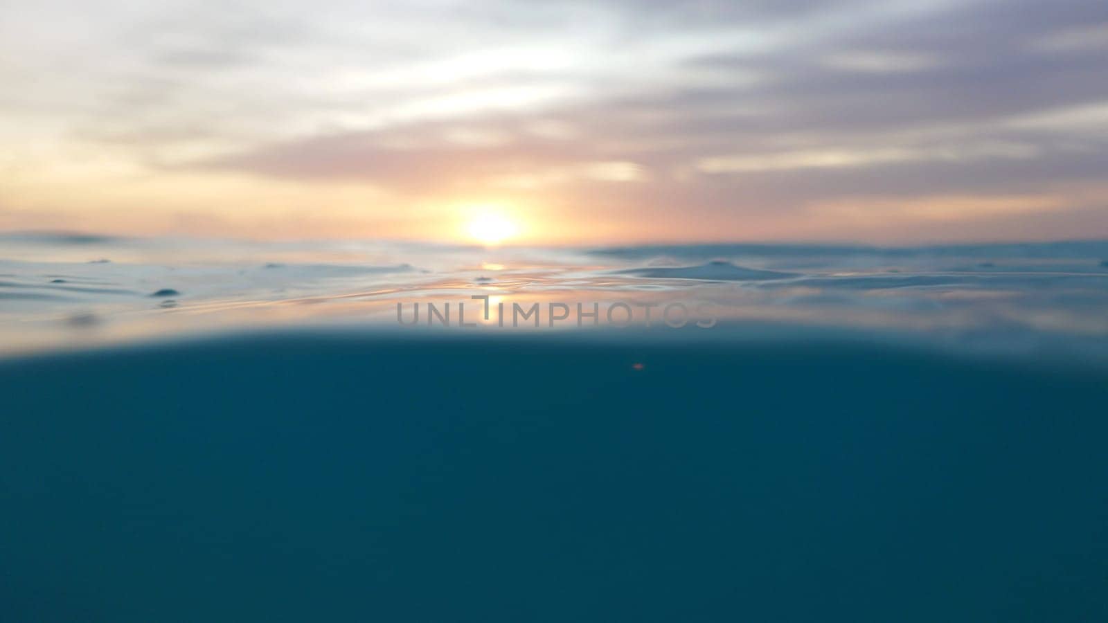 Split view of a beautiful sunset over a calm ocean, showing both the surface and the underwater world, creating a serene and peaceful atmosphere