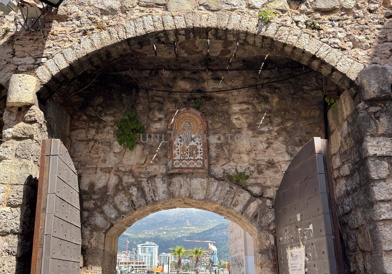 Budva, Montenegro - April 18, 2025: The historic stone arch of the old town, decorated with religious iconography, is located in the cultural heritage site of the coastal city