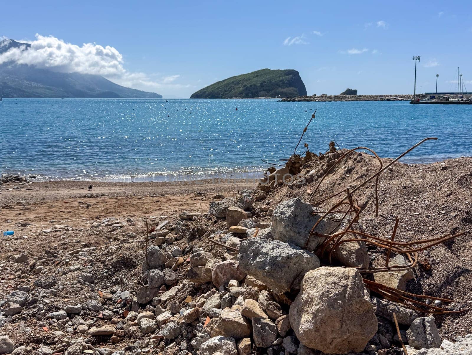 Budva, Montenegro - April 18, 2025: A coastal landscape showcasing renovation and restoration, with debris in the foreground and serene views of the water, highlighting the beauty of nature and renewal