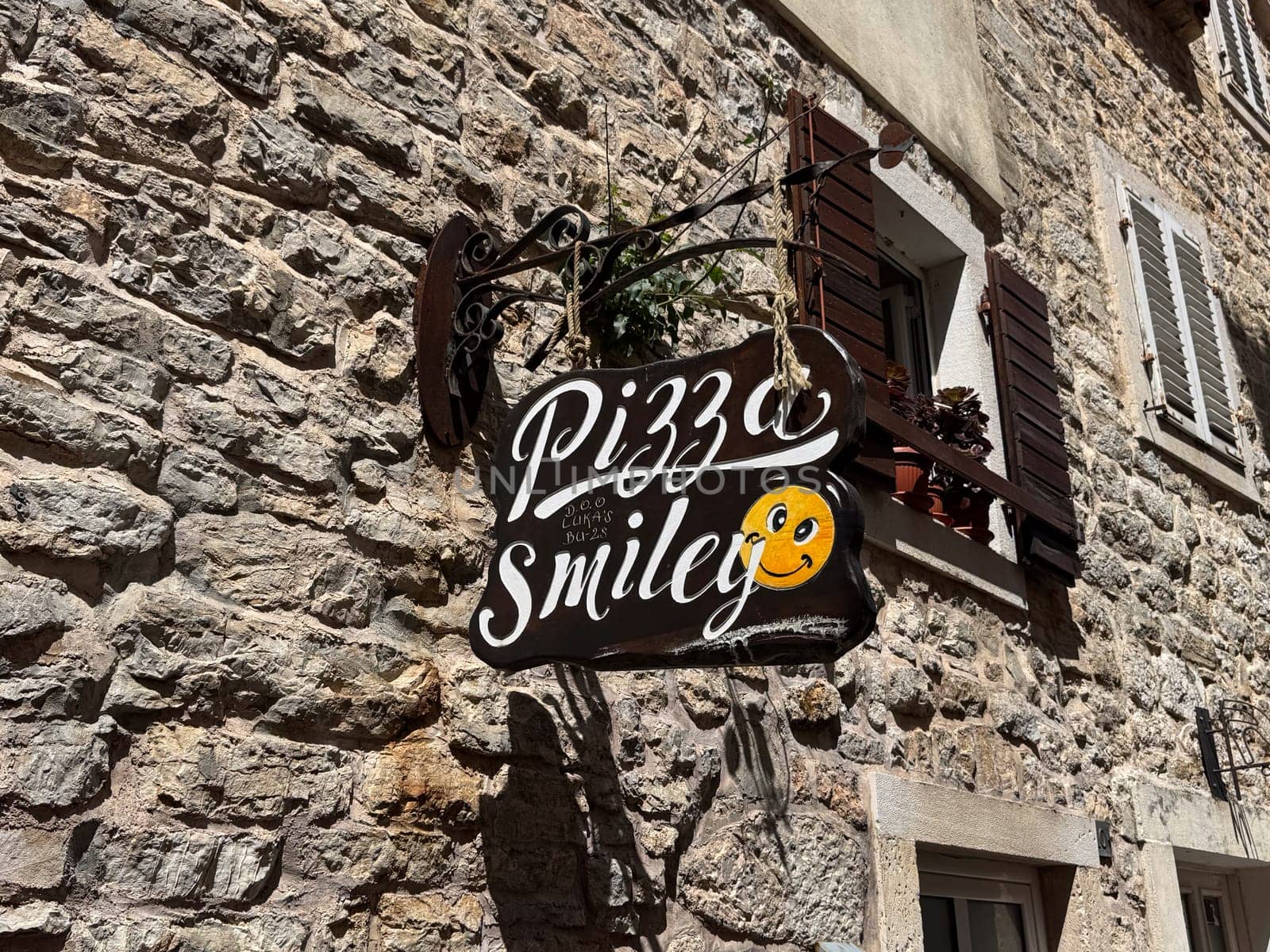 Budva, Montenegro - April 18, 2025: Pizza Smiley sign on a rustic stone wall in the Old Town. inviting joy and a sense of community through its fun design