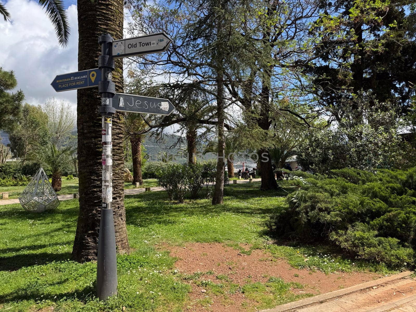 Budva, Montenegro - April 18, 2025: Directional signs in a tranquil park-like environment inviting visitors to explore local attractions and nature