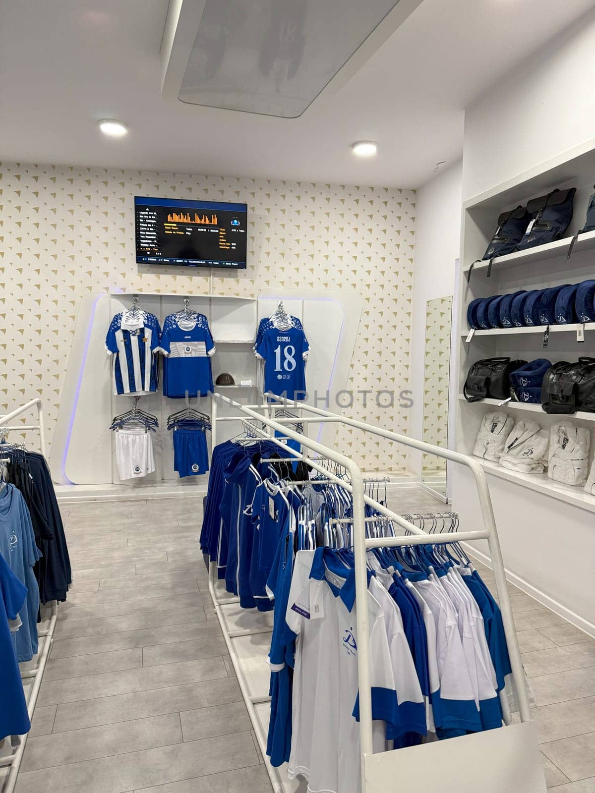 Official Dinamo Tbilisi fan shop interior with football jerseys, team shirts, and branded merchandise in blue and white on organized display racks