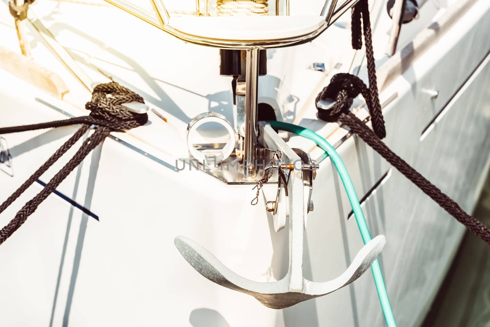 Sailboat anchor in sunlight showing nautical details and rope, background