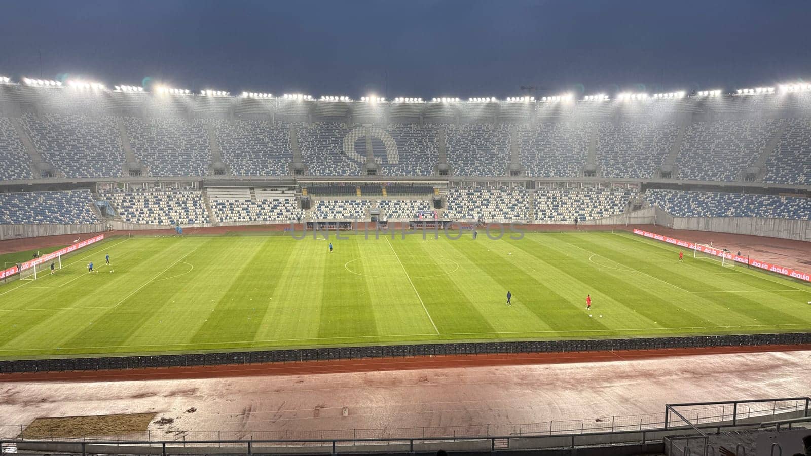 Tbilisi, Georgia, April 9, 2025: Dinamo Tbilisi football stadium during pre match warmup, viewed from the stands with players on the field and seating area in the background