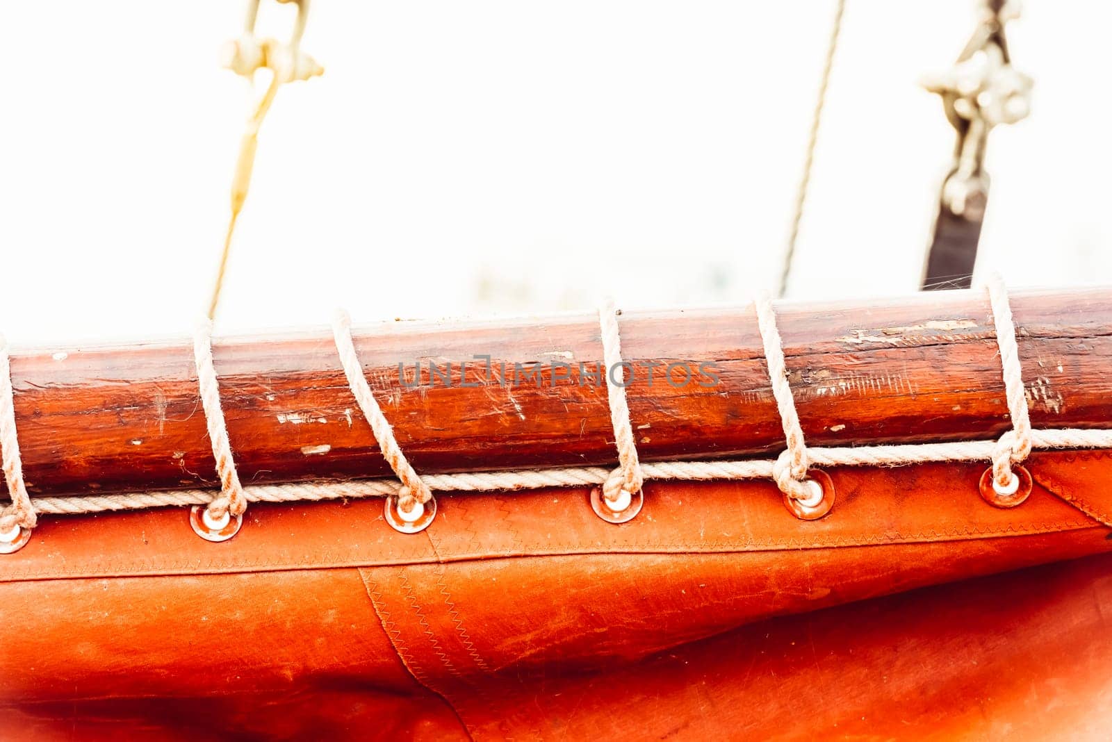 Sailboat mast and ropes with vibrant orange sail creating nautical background