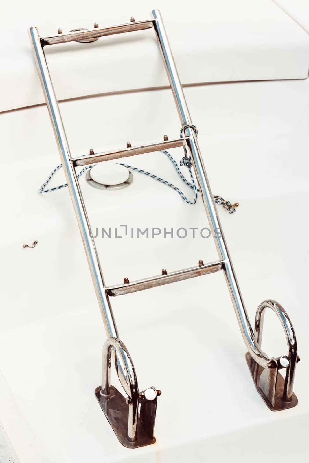 Boat ladder on white deck with rope, maritime equipment background