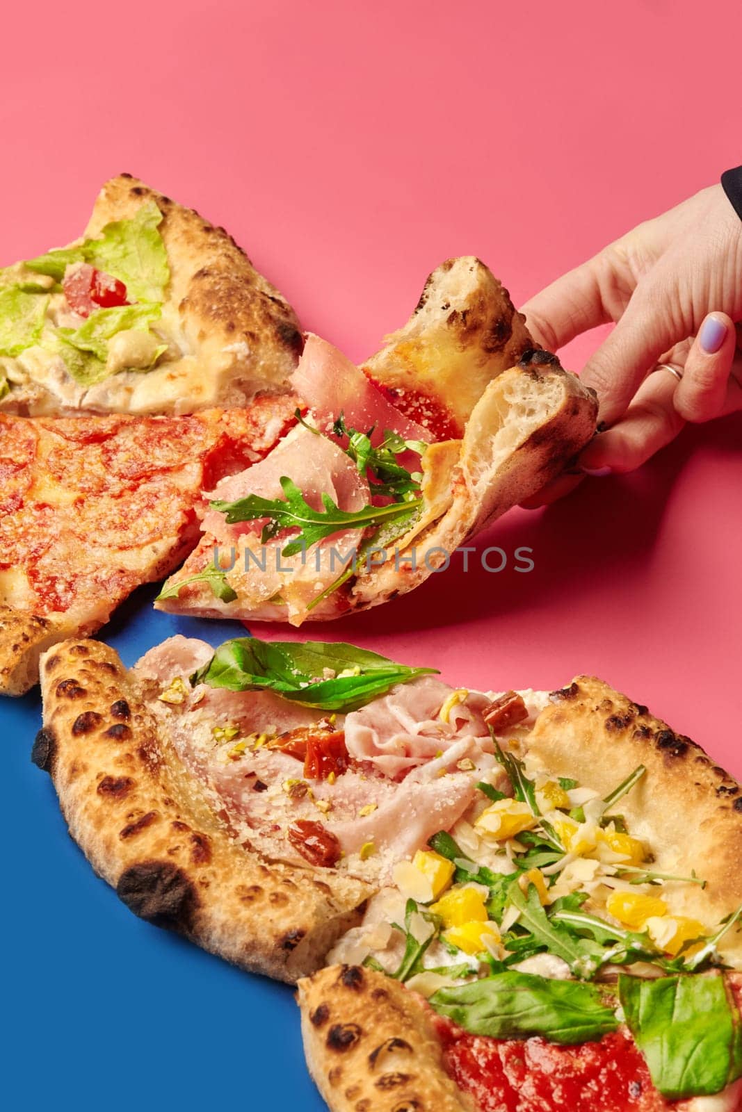 Hand grabbing a slice of pizza with assorted toppings, showcasing a vibrant and appetizing culinary experience