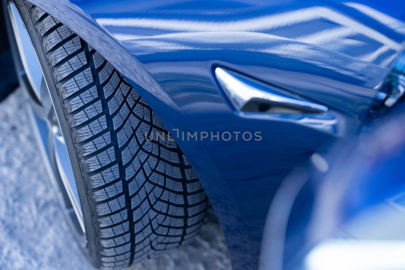Close up winter tires on a road. Driving car with winter tire wheel on road. Detail of car tires in winter on the road. Headlight turning off switching of car LED headlights. New modern electric car.