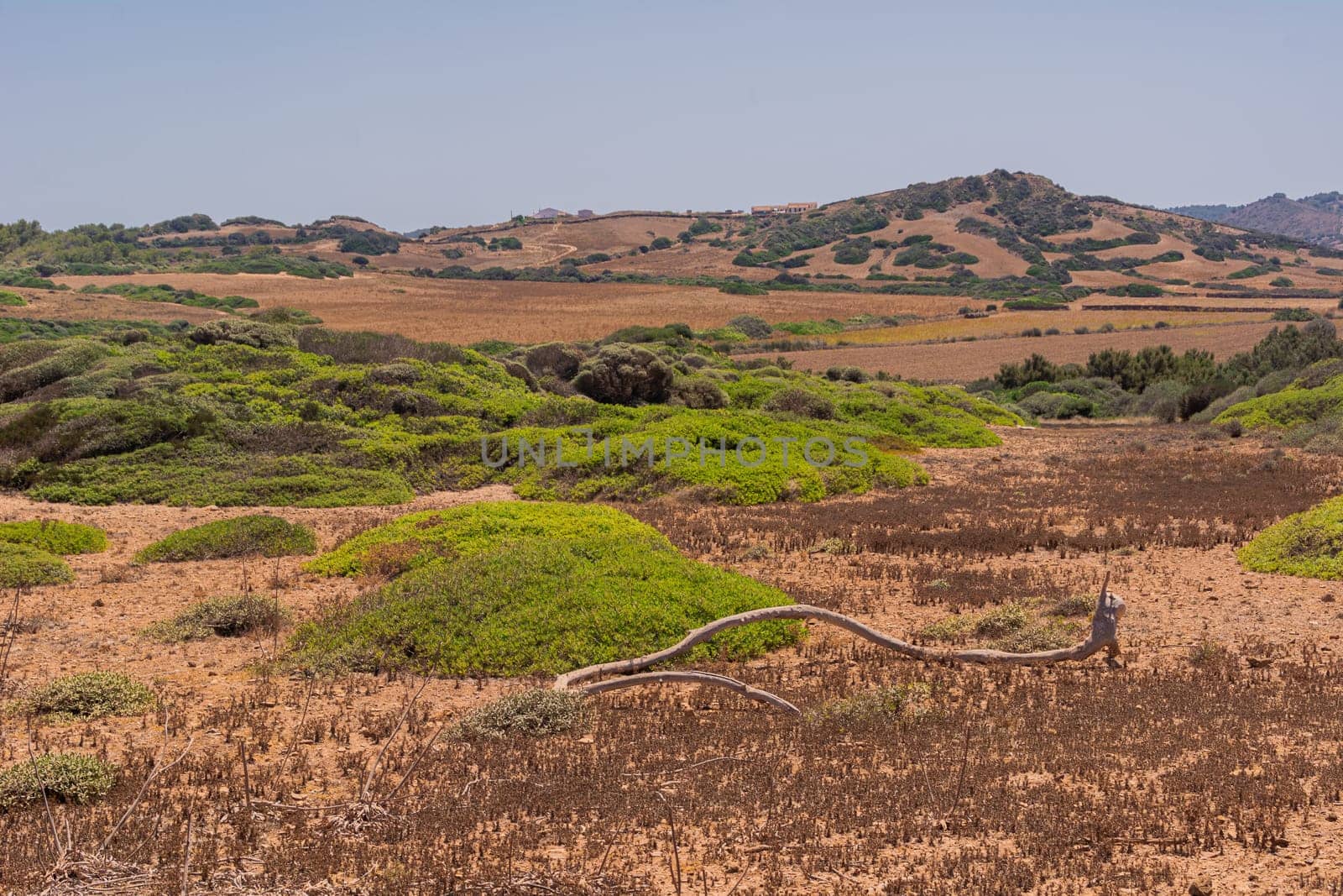 Island landscape of the north of the island of Menorca, dunes.Cloudy and bright skies, mountains in the background, bushes, sea, roads, no people.