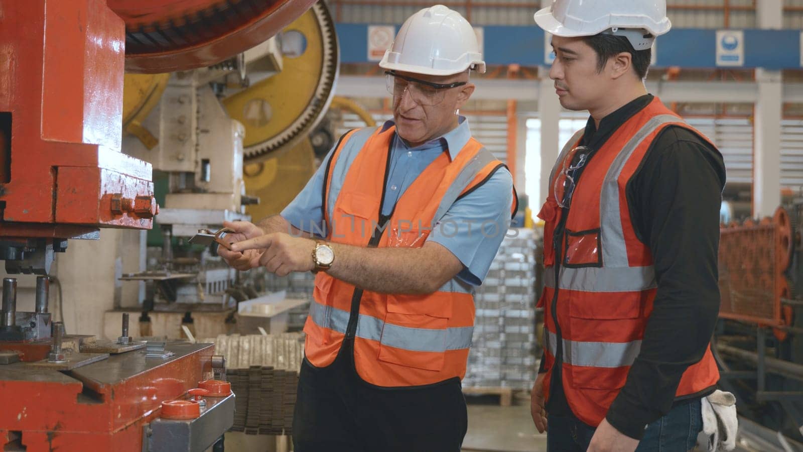 Two engineers talking together in roof steel metal manufacturing factory industry, engineering worker man standing explaining for maintain of metal sheet stamping machine, teamwork concept