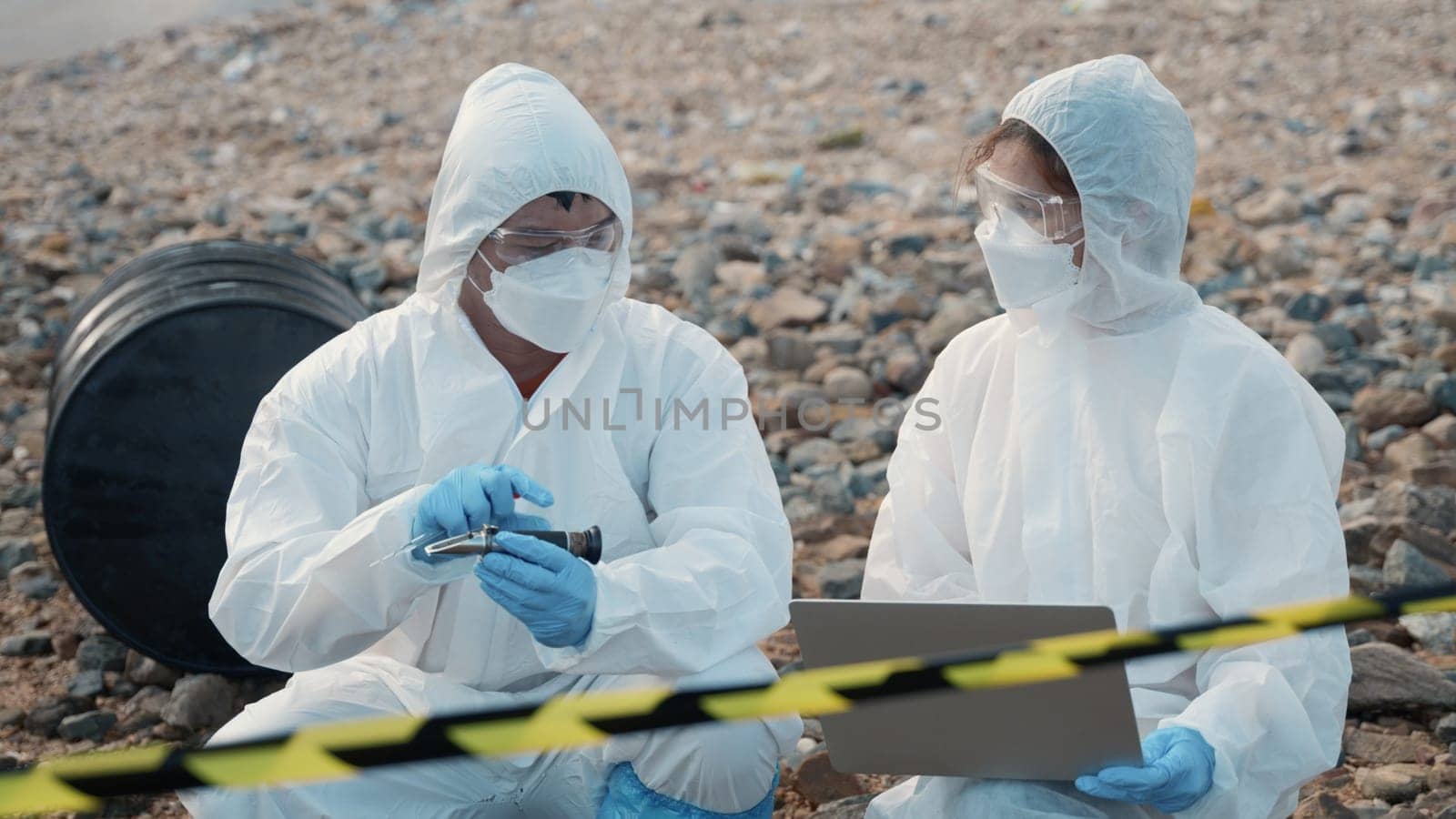 Ecologist sampling water from the river to water quality tester and peek into, Biologist wear protective suit and mask collects sample of waste water from industrial for pH meter, problem environment