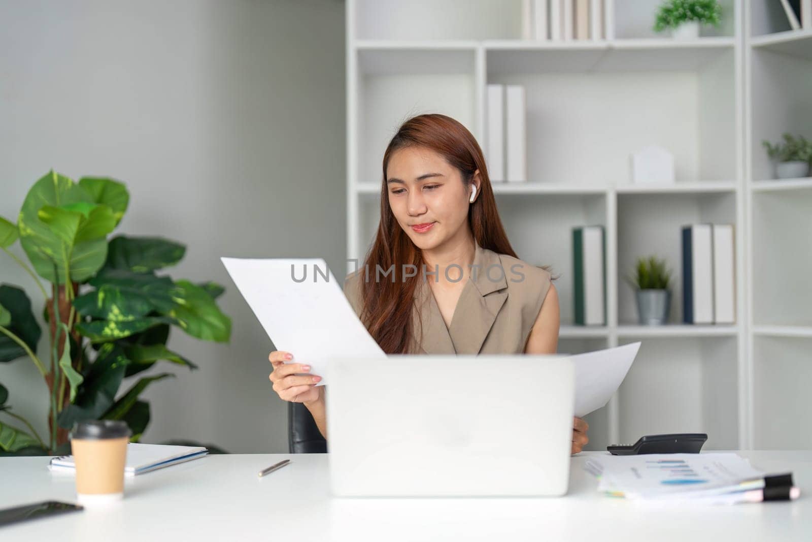 While on a video call, a woman reviews her documents to ensure accuracy and clarity, highlighting the importance of effective communication.