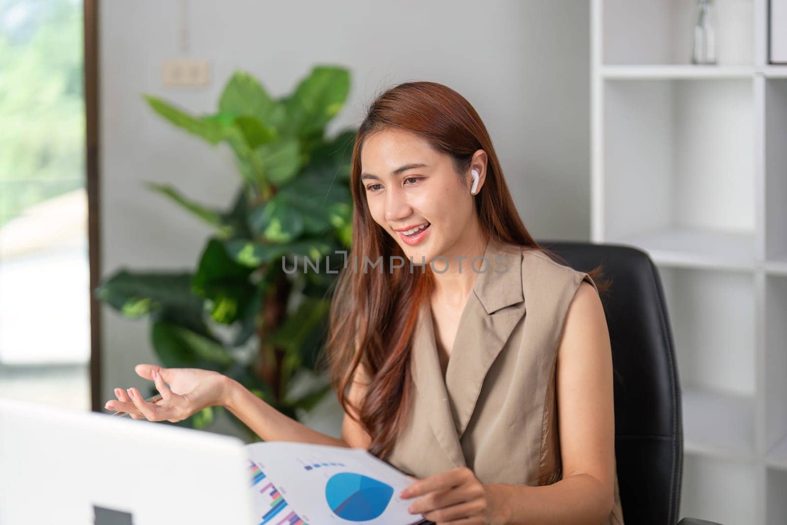 A confident businesswoman uses her earphones for clear communication while presenting data online, exemplifying modern presentation techniques.