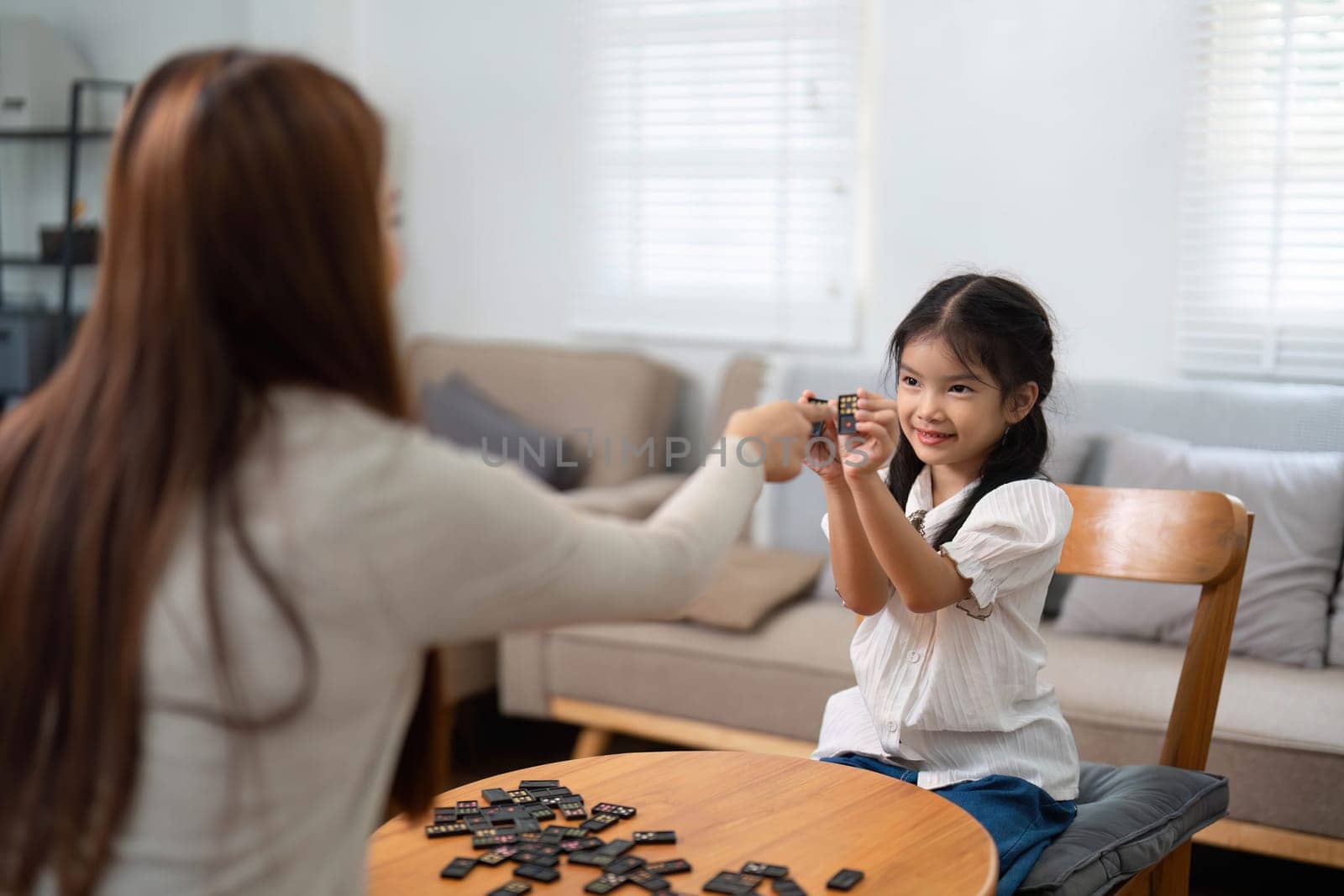 During a lively game session, a little girl smiles as she engages with her mother, enhancing her skills in a fun and interactive way.