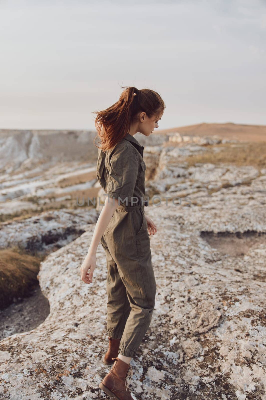 Adventure in the wilderness a woman in a green jumpsuit ascending a rocky outcropping on her journey